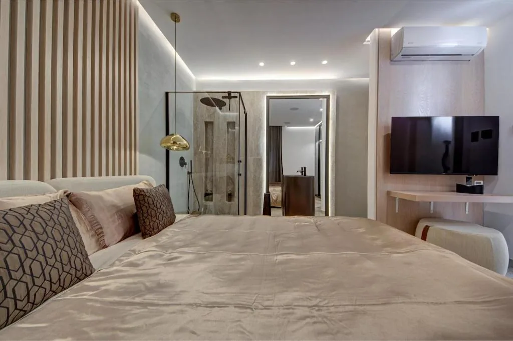 A bedroom with its shower open behind glass