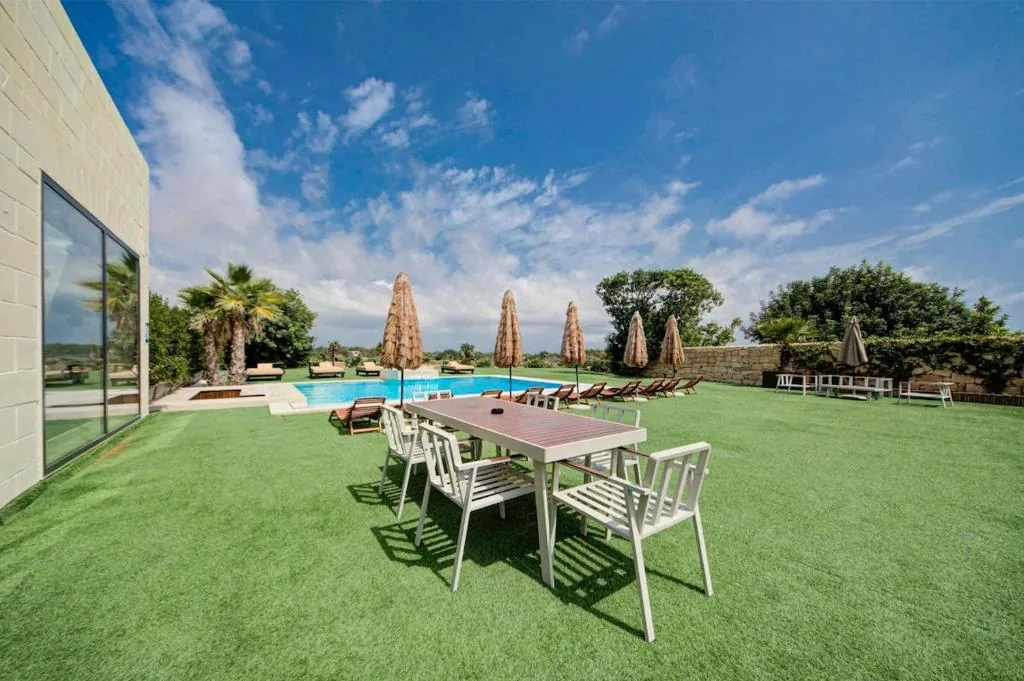 The dining table on the lawn with the pool beyond