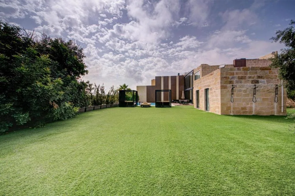 The lawn running the length of the house, with outdoor showers set into the limestone