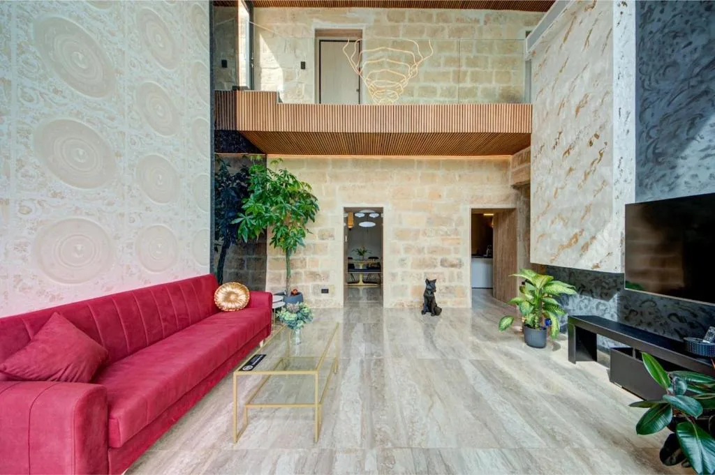 The double-height living room in bare limestone, with the mezzanine above